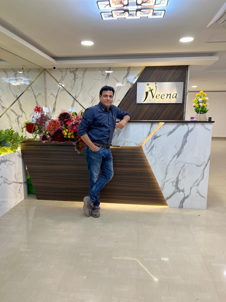 Dr. G. Nirmal standing beside the reception desk at Niveena Homeo Clinic in Chennai