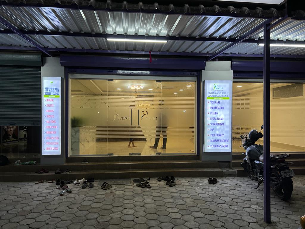 Glass-front entrance of Niveena Homeo Clinic illuminated at night in Chennai